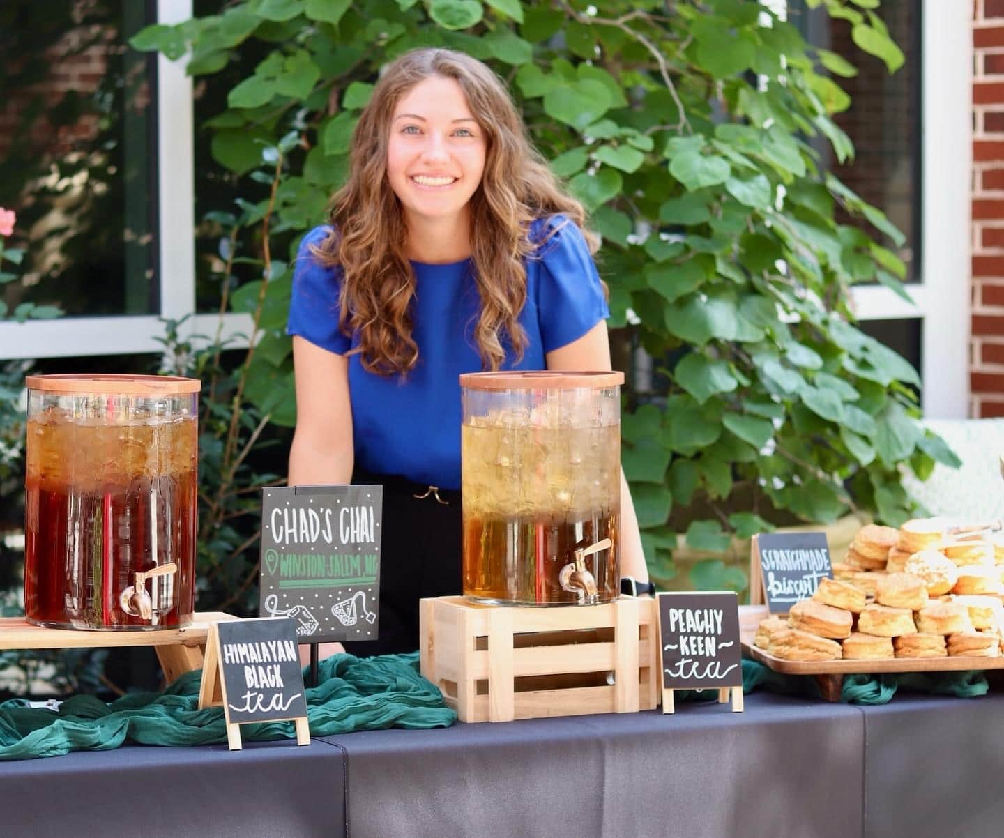 Rachel smiles behind table with large container of iced drink
